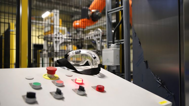 Tehtaan laitteiston ohjain, taustalla robotiikkaa.
