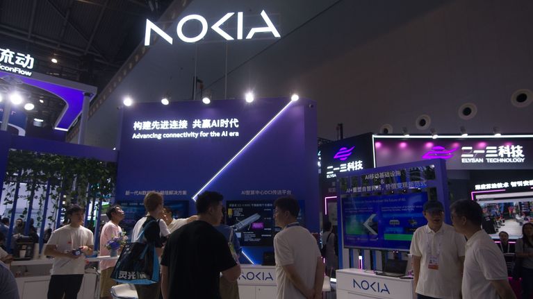 Useita ihmisiä seisoo Nokia-näyttelyosastolla messuilla suurten näyttöjen ja tekstitunnusten edessä.