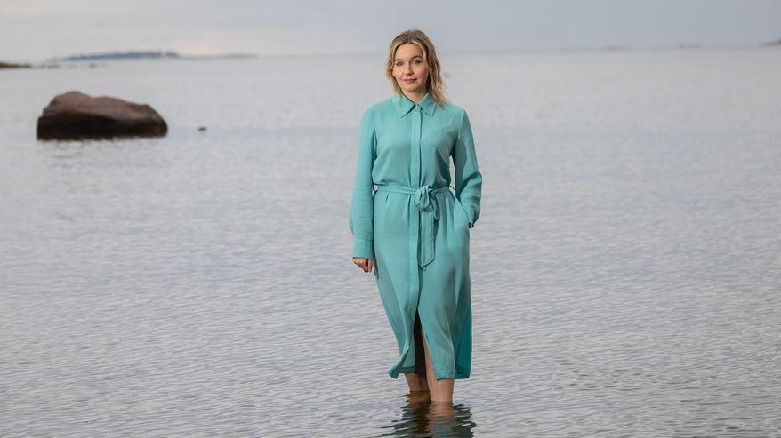 Julia Sangervo seisoo rantavedessä sinertävässä mekossa.