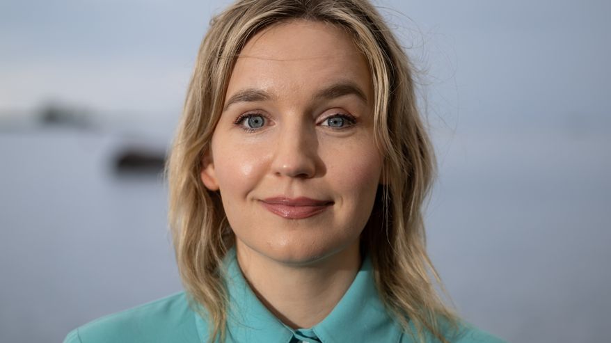 Julia Sangervo seisoo rantavedessä sinertävässä mekossa.