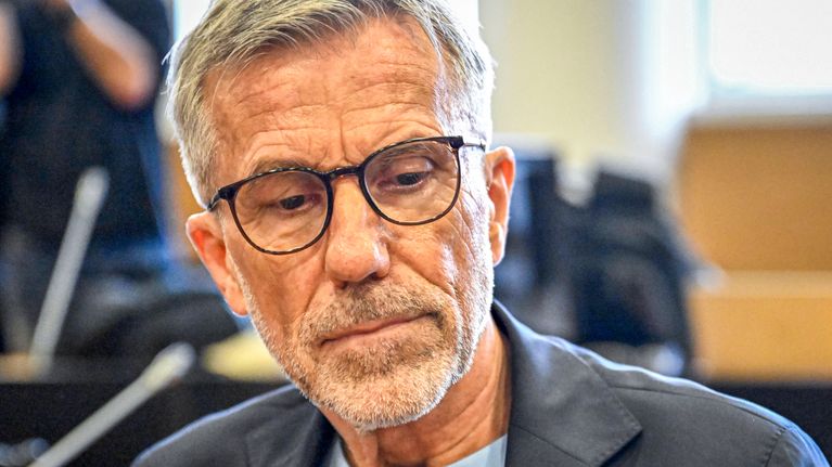 Rolf Nordmo istuu sisätiloissa pöydän ääressä, taustalla näkyy muita ihmisiä.