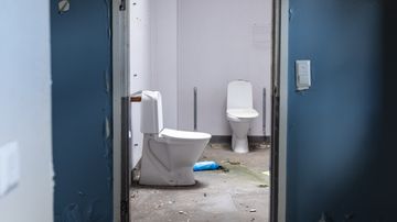 Kaksi wc-istuina tyhjillään olevassa, entisessä laitoskiinteistössä.