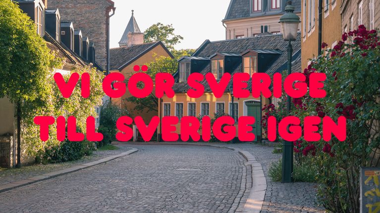 Kapea, kivinen katu värikkäiden rakennusten välissä; kuvassa punainen teksti "VI GÖR SVERIGE TILL SVERIGE IGEN".