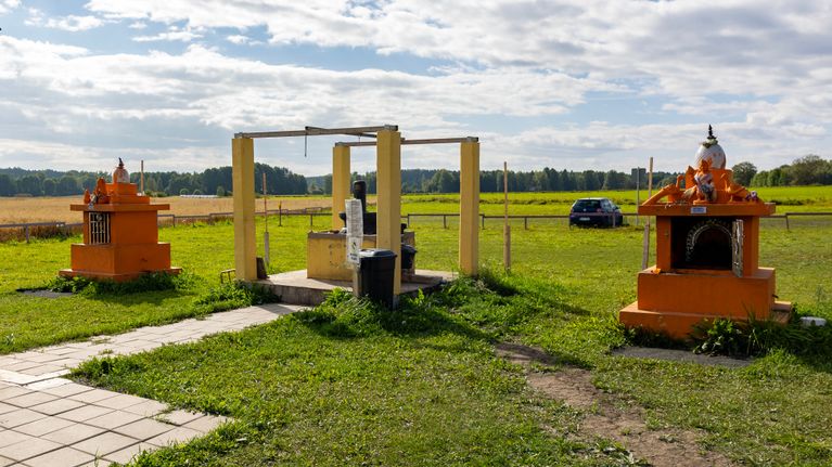 Kolme alttaria ulkona nurmikolla. Reunoissa olevat alttarit ovat kirkkaan oransseja ja keskellä on keltainen alttari, jossa on Shiva jumala patsas.