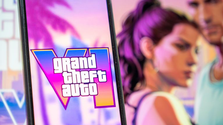 Älypuhelimen näytöllä lukee “Grand Theft Auto VI”, taustalla kaksi piirrosmaista hahmoa ja värikäs maisema.