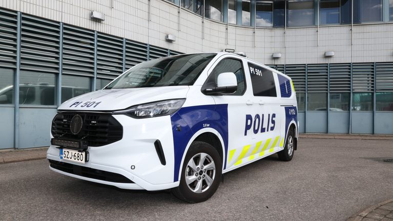 Poliisin pakettiauto valkoisella pohjavärillä ja poliisin teksti- ja heijastinteippauksilla.