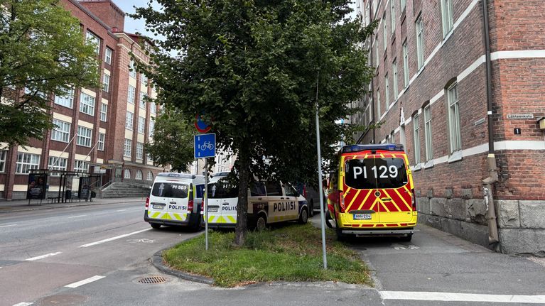 Hälytysajoneuvoja kerrostalon edessä