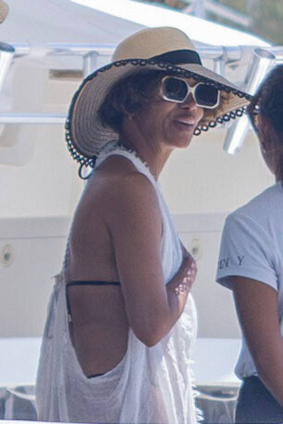 Halle Berry hymyili jahdin kannella valkoisessa läpikuultavassa rantatunikassa, jonka alta vilahtivat tummat bikinit. Olkihattu ja valkoiset aurinkolasit viimeistelivät lomailijan tyylin.