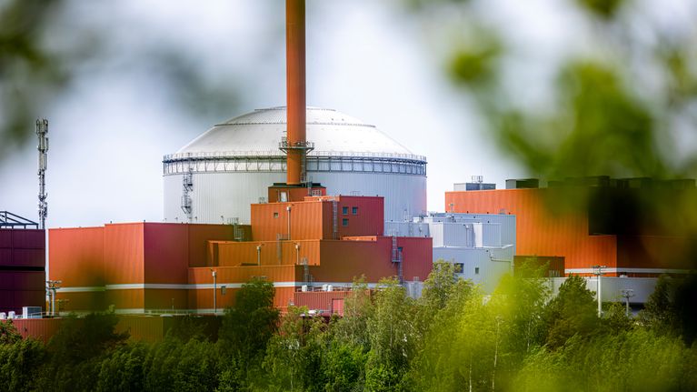 Kuvassa näkyy ydinvoimalaitos vehreän maiseman ympäröimänä, keskellä vesistöä ja infrastrukturia.