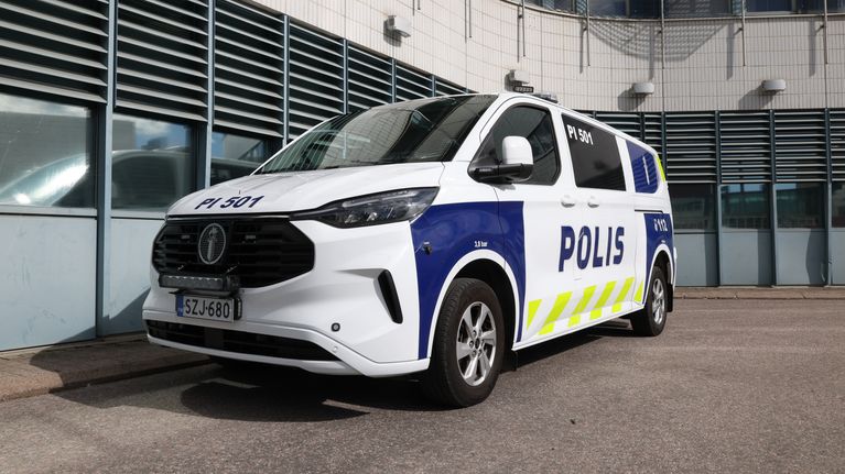 Poliisin pakettiauto valkoisella pohjavärillä ja poliisin teksti- ja heijastinteippauksilla.