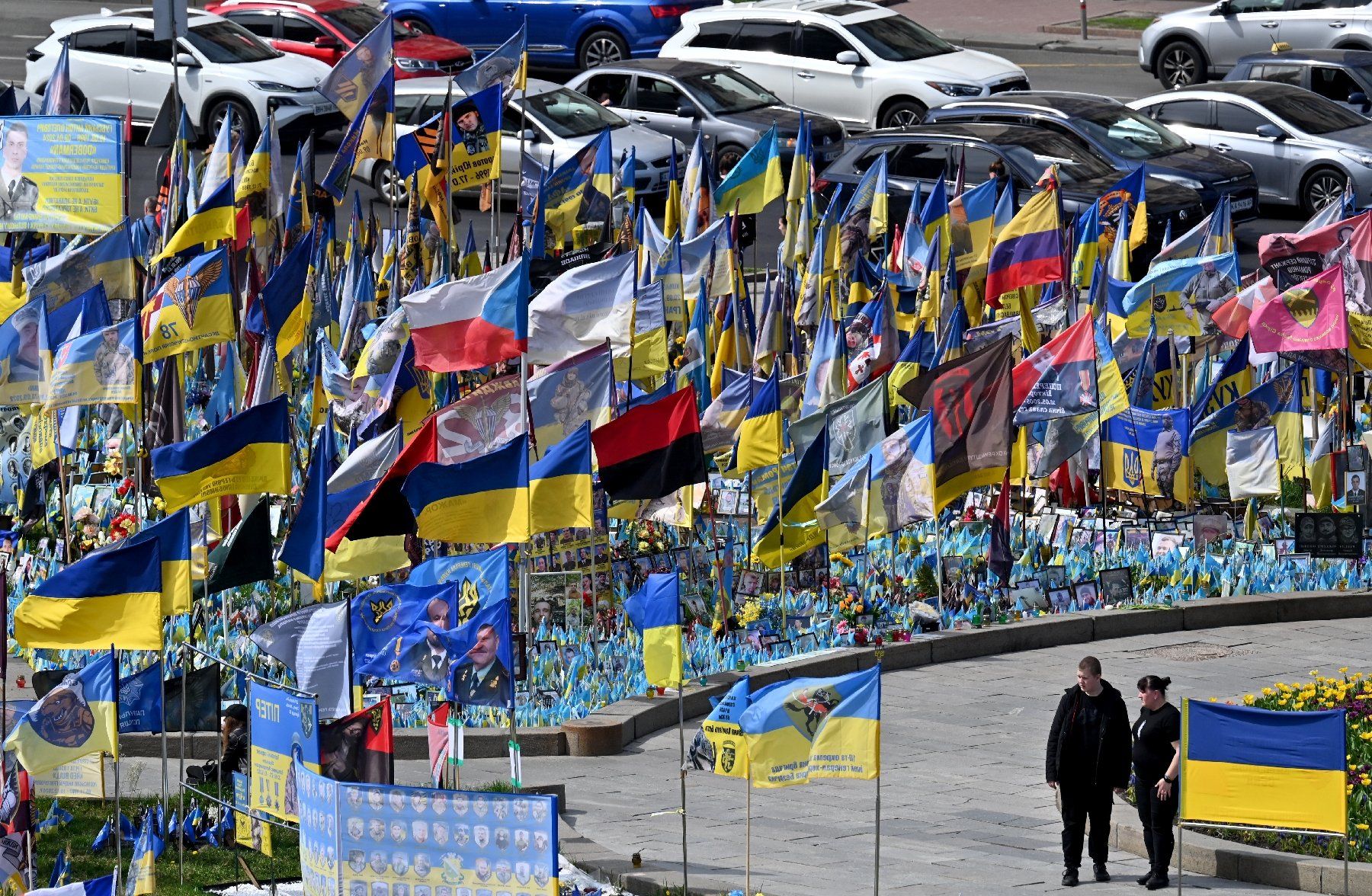 Un couple devant des drapeaux et des portraits de soldats au mémorial improvisé pour les combattants ukrainiens et étrangers tombés au combat, sur la place de l'Indépendance à Kiev, le 19 avril 2025 en Ukraine