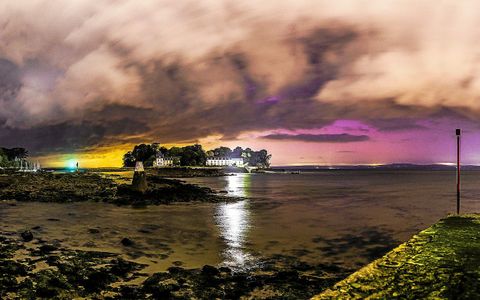 Le ciel magenta à droite de l’île Tristan révèle la présence d’aurores boréales particulièrement intenses sur cette photo prise dans la nuit du 22 au 23 avril 2023. À gauche de l’île, ce sont les lumières de couleur orange de la ville de Brest qui sont bien visibles.