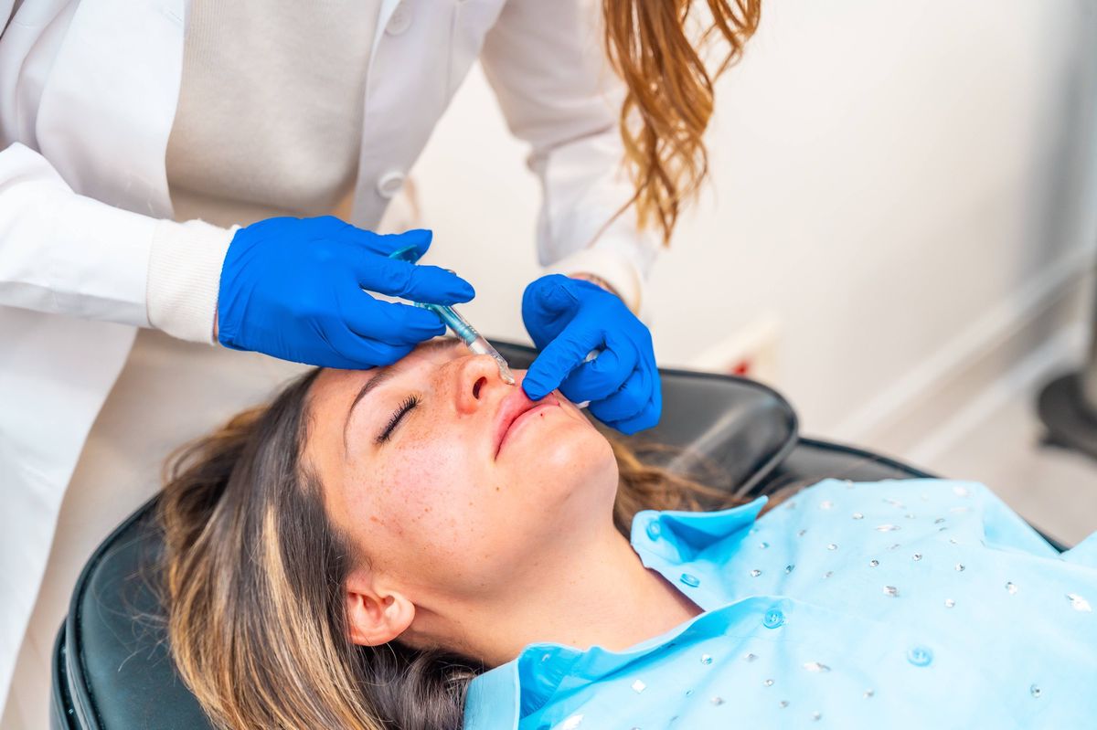 Un praticien injecte du botox dans le visage d’une femme.