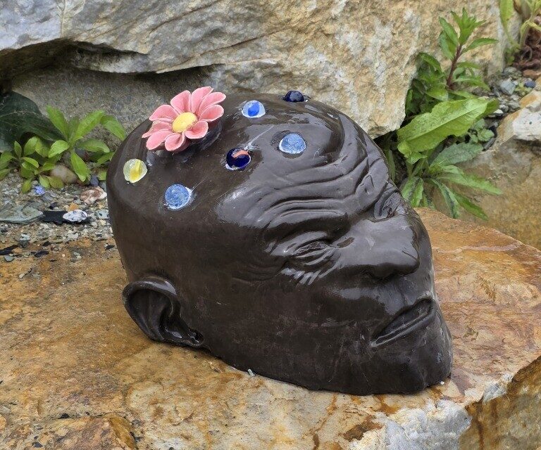 Une tête ornée de fleurs observe les passants.