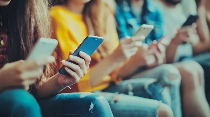 nomophobie accro dépendant au téléphone surtout les jeunes Ma Santé Des jeunes atteints de nomophobie, les yeux rivés sur leurs écrans de téléphone.