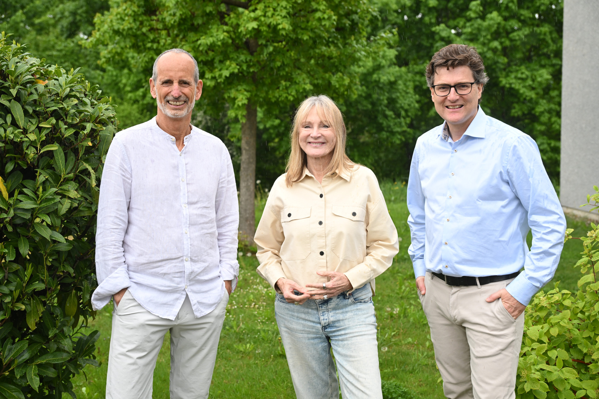 Roland Liebscher Bracht, Petra Bracht et Christoph Glaser discutent des secrets de la longévité dans un jardin verdoyant.
