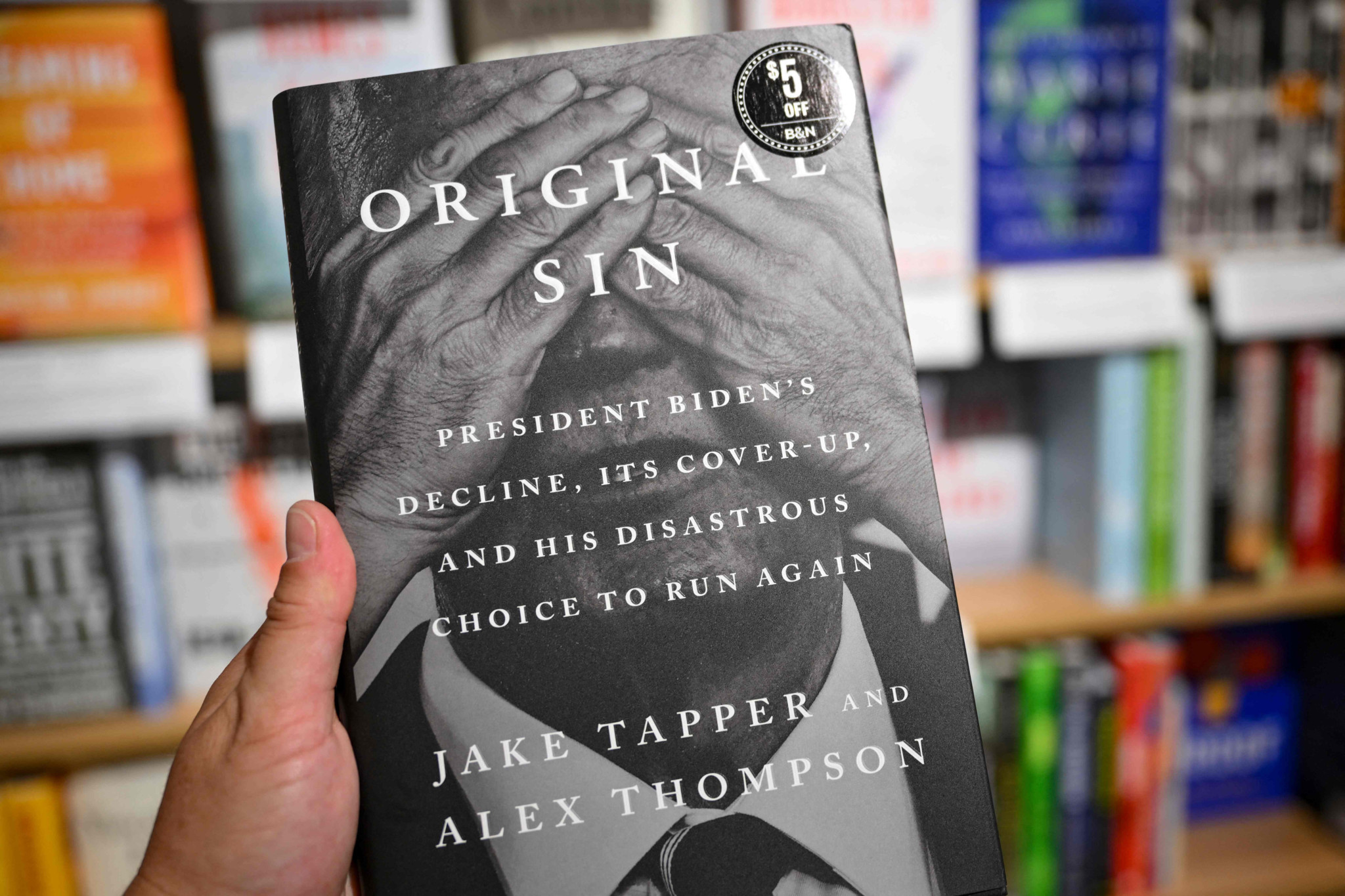 Une personne tient le livre «Original Sin: President Biden’s Decline, Its Cover-Up, and His Disastrous Choice to Run Again», par Jake Tapper et Alex Thompson, dans une librairie à New York, le 20 mai 2025.