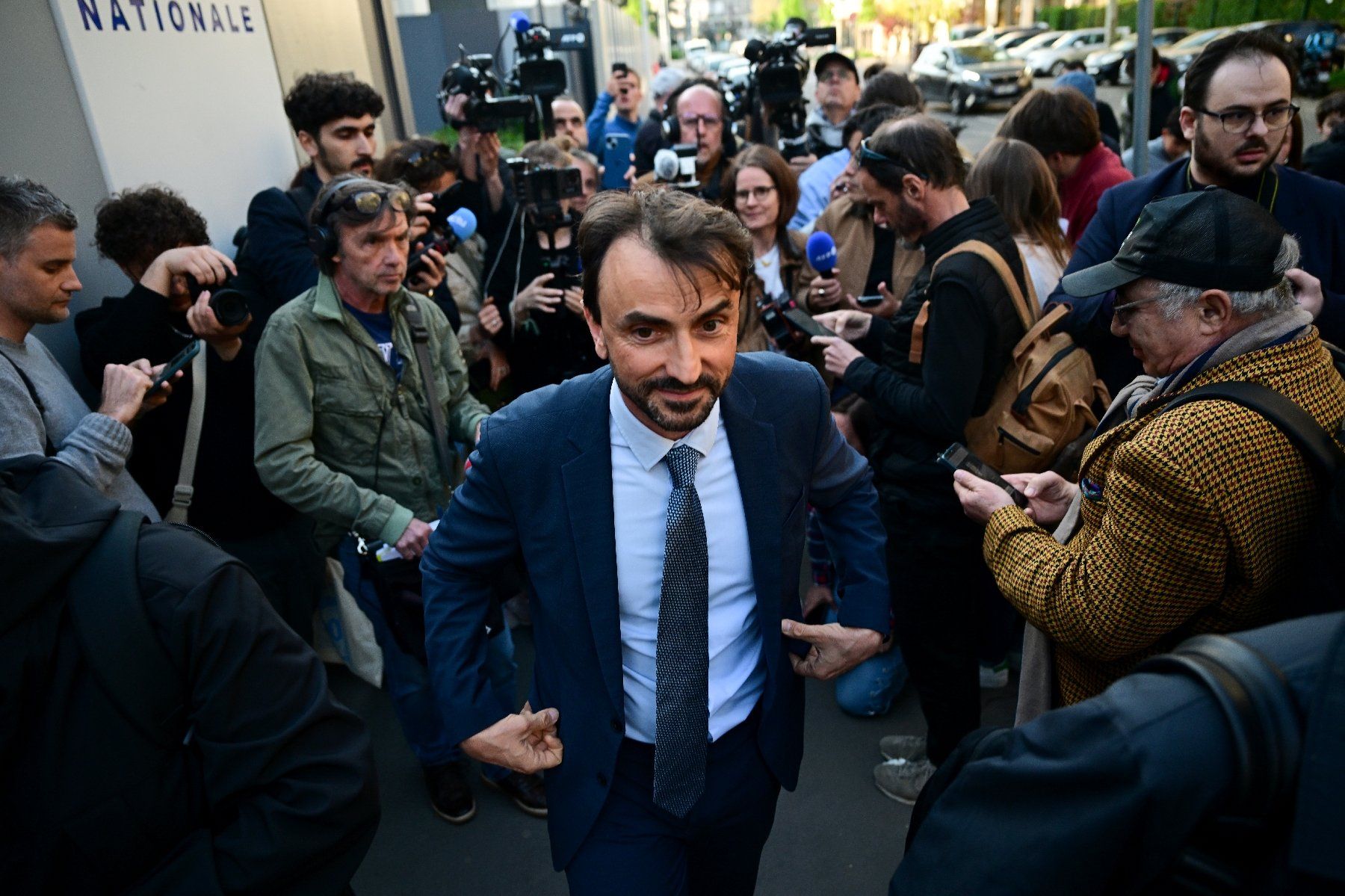 Le maire de Lyon, Grégory Doucet (C), sort après avoir été remis en liberté après plus de 10 heures d'interrogatoire dans le cadre d'une enquête pour détournement de fonds publics, à la préfecture de police de Lyon, le 9 avril 2025