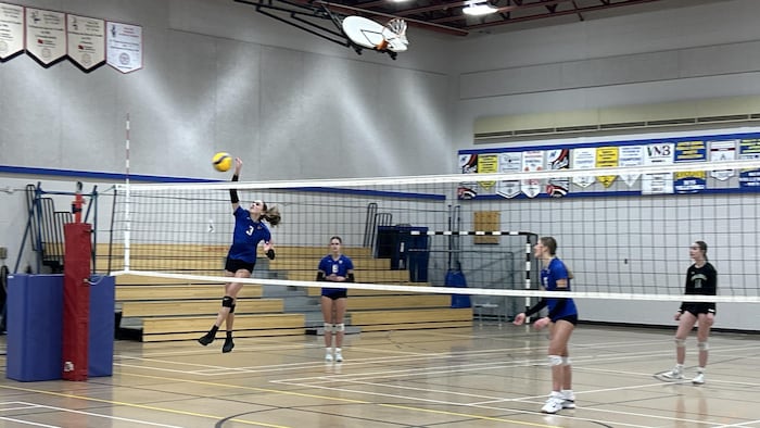 Quatre joueuses de volleyball s'exercent dans un gymnase.