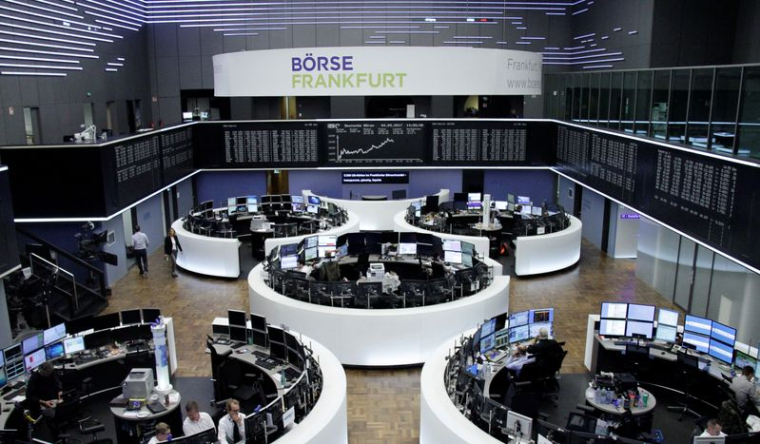 Des traders travaillent devant le tableau de l'indice boursier allemand DAX, à la bourse de Francfort