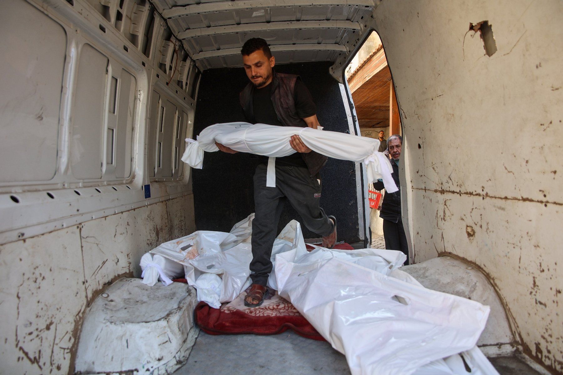 Un Palestinien transporte le corps d’un enfant dans une camionnette contenant les dépouilles d'autres personnes tuées lors de frappes aériennes israéliennes, dans l’enceinte de l’hôpital Al-Ahli Arab de Gaza-Ville, le 21 mai 2025