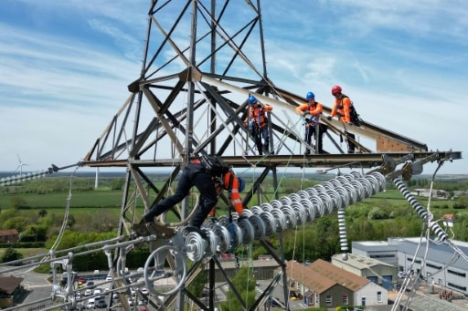 Des apprentis suivent une formation sur un pylône au centre de formation de National Grid à Eakring, dans le centre de l'Angleterre, le 28 avril 2025, perchés à 45 mètres de hauteur © AFP Darren Staples