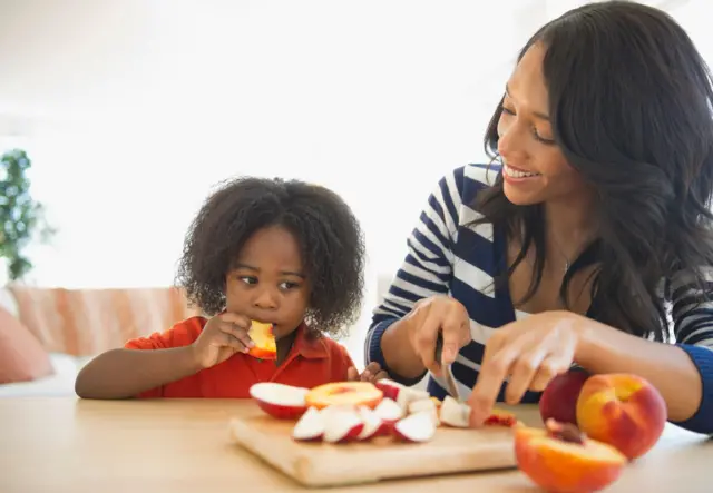 Mère afro-américaine coupant des pommes pour son fils