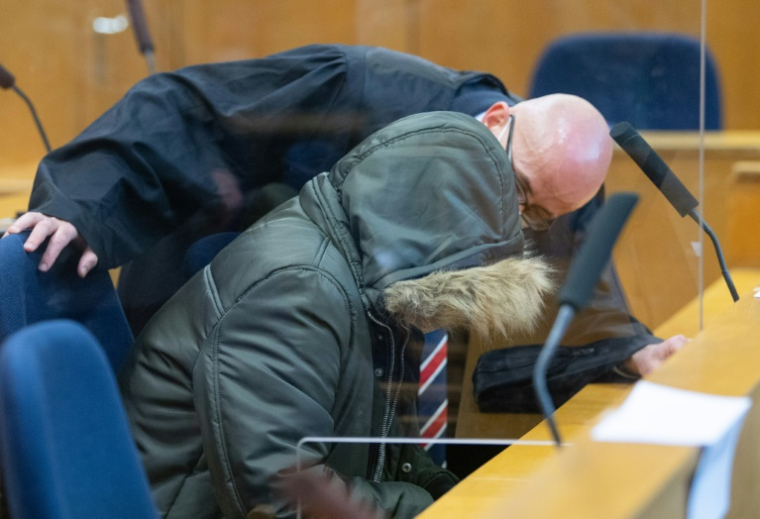 Alaa Moussa (G), un médecin syrien accusé de crimes contre l'humanité, parle avec son avocat à l'ouverture de son procès, le 19 janvier 2022 à Francfort ( POOL / Boris Roessler )