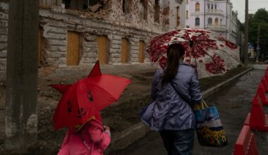 Une mère et sa fille passent près d'un bâtiment détruit par un bombardement russe, le 12 juin 2025 à Soumy, dans le nord-est de l'Ukraine