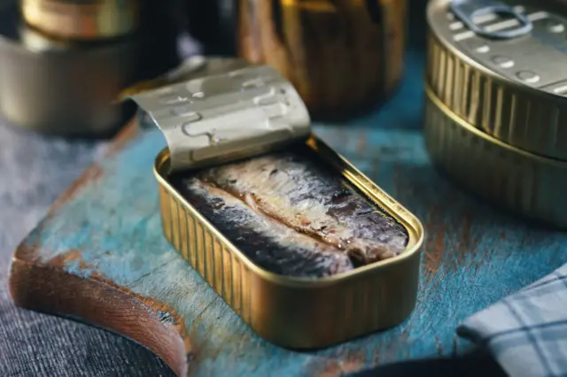 Des sardines dans une boîte ouverte posée sur une planche