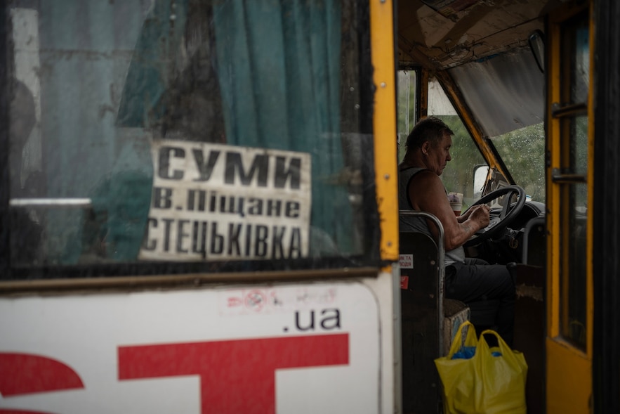 Un chauffeur de bus attend des passagers dans la localité de Stetskivka, proche de la ligne de front, dans le nord-est de l'Ukraine, le 12 juin 2025 