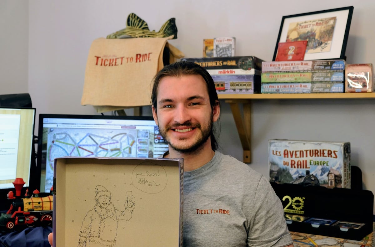 Simon Bellemare montre les prix et cadeaux qu'il a reçu du tournoi mondial du jeu de société Les aventuriers du rail à Paris, en mai 2025.
