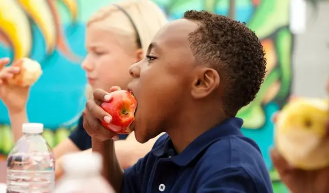Un enfant croque une pomme