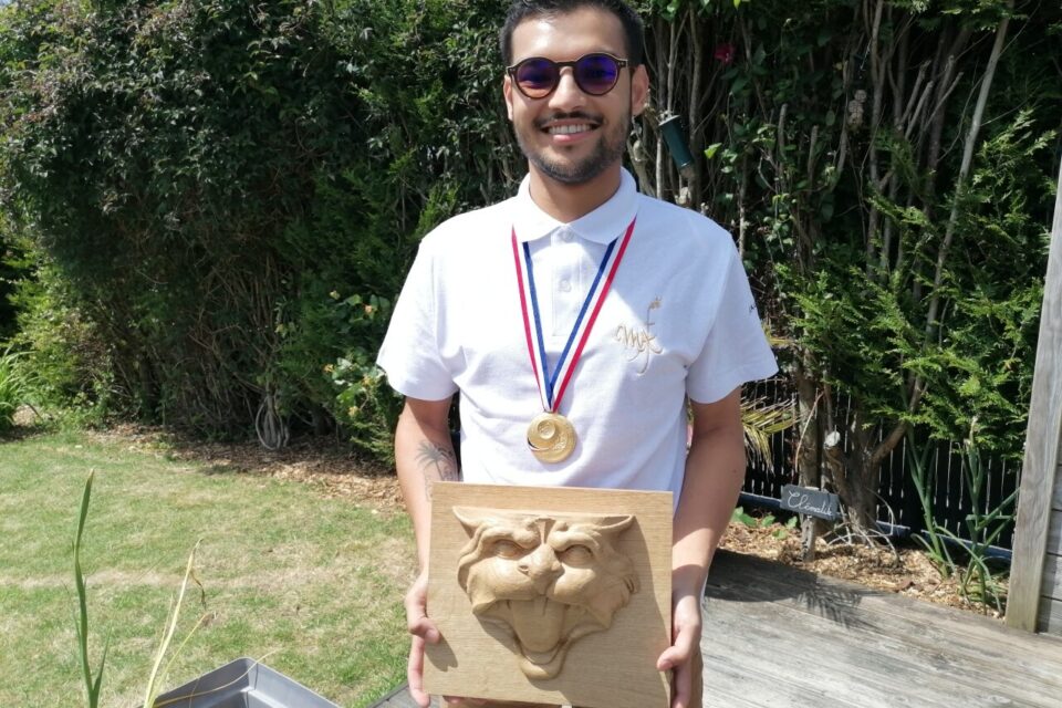 Nicolas Guilbert et la reproduction de miséricorde sculptée sur bois qui lui a permis de décrocher une médaille d'or de meilleur apprenti de France.