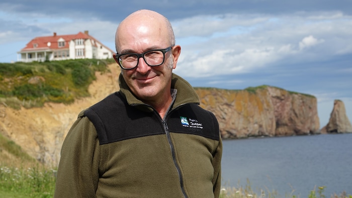 Rémi Plourde pose devant le Rocher Percé.
