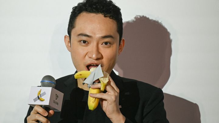 Justin Sun mange la banane de l'œuvre "Comedian" de Maurizio Cattelan, à Hong-Kong, le 29 novembre 2024. (PETER PARKS / AFP)