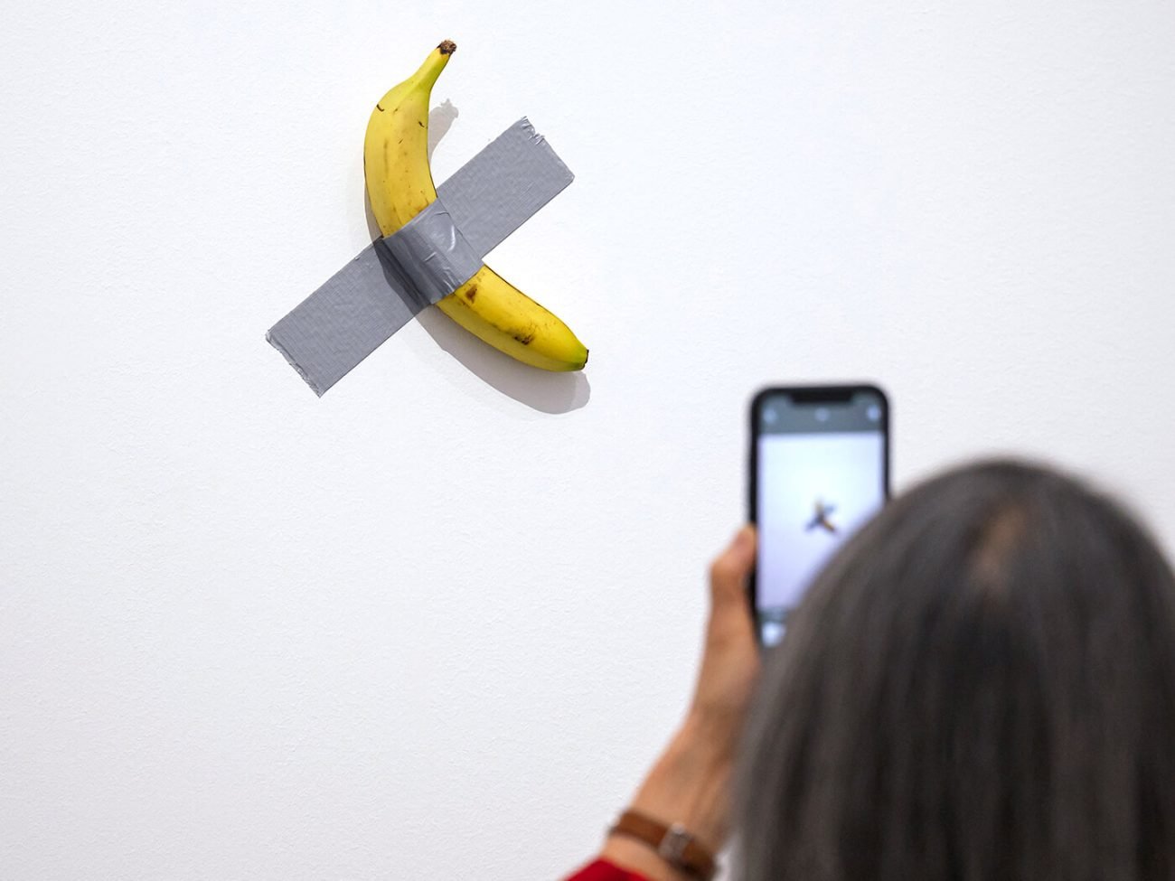 Une visiteuse photographiant l’œuvre « Comedian » de Maurizio Cattelan lors de l’inauguration de l’exposition « Dimanche sans fin » au Centre Pompidou Metz