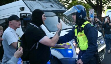 Des manifestants font face à un policier lors d'un rassemblement dans le centre d'Epping, au nord-est de Londres, le 20 juillet 2025