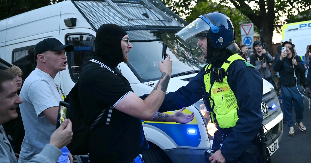 Des manifestants font face à un policier lors d'un rassemblement dans le centre d'Epping, au nord-est de Londres, le 20 juillet 2025