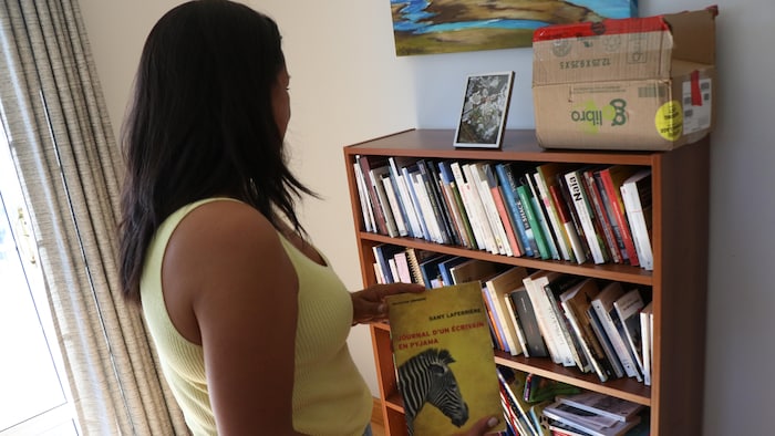 Naomi Fontaine de dos avec un livre en main.