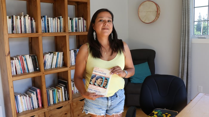 Naomi Fontaine tient fièrement le livre Je suis une maudite sauvagesse.