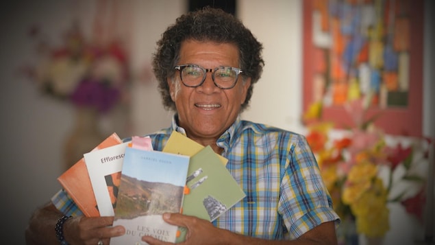L’artiste Gabriel Osson avec plusieurs de ses œuvres dans ses mains.