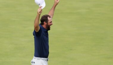 Il lève les deux bras, avec sa casquette dans la main droite, pour célébrer sa victoire.