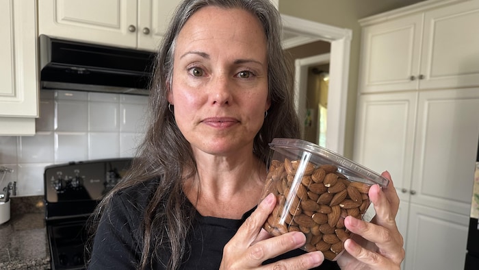 Une femme dans sa cuisine tient un paquet d'amandes.