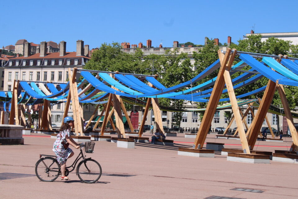 Des passants se posent sous les ombrières de la place Bellecour, à Lyon.