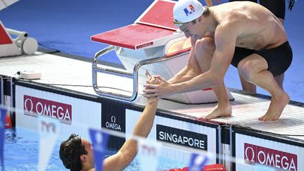 Léon Marchand (à droite) et Yann Le Goff (à gauche) après le relais 4x100 m 4 nages des Mondiaux de natation, à Singapour, le 3 août 2025. (FRANCOIS-XAVIER MARIT / AFP)