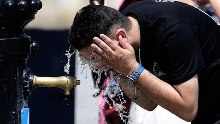 Un homme se rafraîchit à une fontaine à Séville (Espagne), le 12 août 2025. (CRISTINA QUICLER / AFP)
