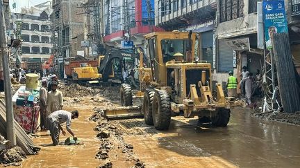 Des ouvriers utilisent des engins lourds pour dégager la boue d'une rue à Mingora, dans la province montagneuse de Khyber Pakhtunkhwa (Pakistan), frappée par la mousson, le 16 août 2025. (MEHBOOB UL HAQ / AFP)