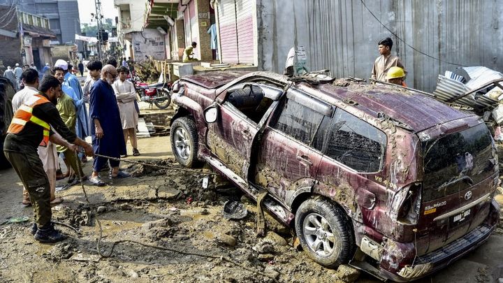 Les sauveteurs et les résidents locaux retirent une voiture de la boue et des débris, dans le district de Buner, au nord du Pakistan, le 16 août 2025. (HASHAM AHMED / AFP)