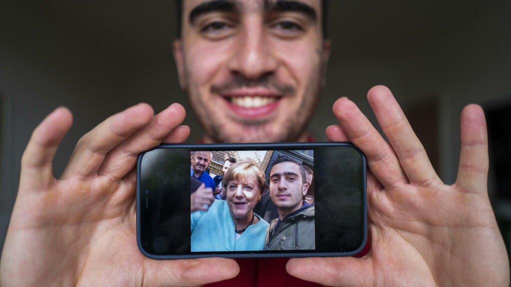 Anas Modamani est un réfugié Syrien qui vit à Berlin. Il montre un selfie qu'il a pris avec la chancelière allemande Angela Merkel devant un centre de réfugiés à Berlin, le 10 septembre 2015, alors qu'il avait 18 ans.